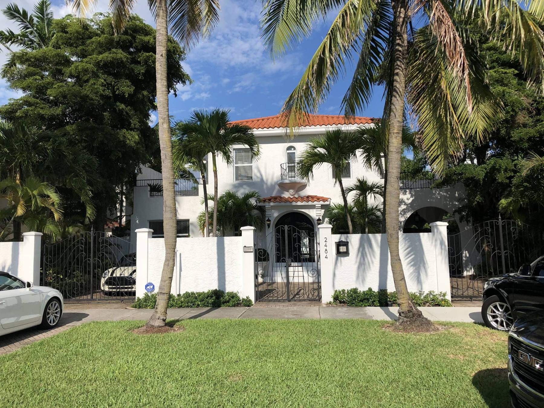 A Miami home behind a white gate with palm trees, inspected by Reliable Inspections